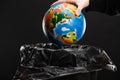 Cropped view of woman throwing away globe in trash bin isolated on black, global warming concept Royalty Free Stock Photo