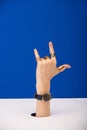 View of woman with wristwatch and golden rings showing rock sign  on blue Royalty Free Stock Photo