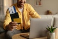 Closeup of young black guy using laptop and booking hotel online with credit card, holding passport with ticket at home Royalty Free Stock Photo