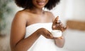 Cropped view of young African American woman using hydrating cream, wearing bath towel indoors, closeup Royalty Free Stock Photo