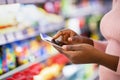 Cropped view of young black woman checking grocery list app on cellphone at supermarket, copy space Royalty Free Stock Photo