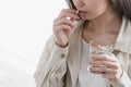 Young woman take pill, holding glass of water