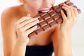 Nothing but sinful indulgence. Cropped view of a young woman biting into a big slab of chocolate. Royalty Free Stock Photo