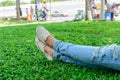 Cropped woman legs in denim with white sneakers resting on grass Royalty Free Stock Photo