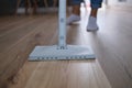 Cropped woman mopping wooden laminate floor using damp mop