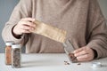 Cropped woman refilling spice jar with dry cayenne pepper from a paper bag. Royalty Free Stock Photo