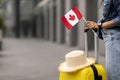 Cropped of woman traveller holding flag of Canada, going abroad