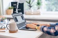 Cropped woman typing on laptop computer while sitting at home. Close up coffee cup and human hands. Distance learning Royalty Free Stock Photo