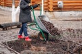 Cropped worker in field clothes applying mulching procedure, collect old dried leaves, bark. Seasonal working in garden. Royalty Free Stock Photo