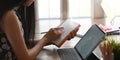 Cropped of young entrepreneur woman taking notes while sitting in front her computer tablet with keyboard case.