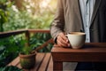 Cropper view of A businessperson holding a coffee cup stands on a wooden porch. AI Generated Royalty Free Stock Photo