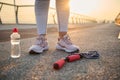 Croppped image of athlete legs wearing pink sneakers and standing on an asphalt treadmill next to a lying down jumping rope and