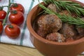 Croquettes with rosemary and cherry on kitchen towel in clay bowl