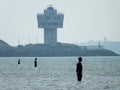 crosby beach with industrial harbour buildings and anthony gormleys another place installation