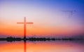 Cross against mountain and lake view at sunset