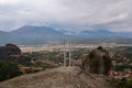 Meteora - Cross with bell on top of rock Aghio Pnevma Holy Spirit. Panoramic view on valley between village of Kastraki Royalty Free Stock Photo