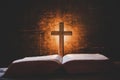 Cross with bible and candle on a old oak wooden table. Beautiful gold background. Royalty Free Stock Photo