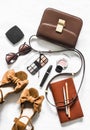 Cross body brown leather bag, suede wedge sandals, cosmetics, sunglasses on a light background, top view. Fashion concept Royalty Free Stock Photo