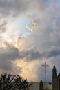 Cross on building with towers and trees against large colorful clouds Royalty Free Stock Photo