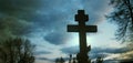 Cross in cemetery in evening under stormy sky. Life and death concept Royalty Free Stock Photo