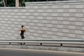 Cross in city at summer. Muscular girl in sportswear with fitness tracker runs along track