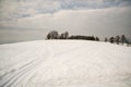 Cross-country skiing track on mountain meadow with few trees and blue sky with clouds