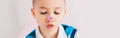 Cross-eyed kid looking at purple violet heart sticker on his nose. Funny hilarious white Caucasian cute adorable child boy making