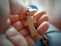 Cross in hands. Person holding wooden holy cross of rosary in hand. Praying rosary. Catholic symbol of faith.