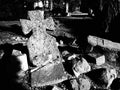 Cross. Headstone at a Catholic Christian cemetery. A lopsided stone monument. Unknown grave in the rays of the low evening sun. Royalty Free Stock Photo