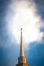 Cross high on top of a church steeple in a blue sky with a white cloud Royalty Free Stock Photo