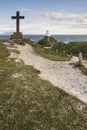 Cross in landscape of Ynys Llanddwyn Island with Twr Mawr lighthouse in background with blue sky