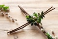 Cross made of branches decorated with boxwood twigs and catkins on wooden background. Creative easter religious concept Royalty Free Stock Photo