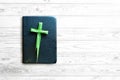 Palm Sunday concept, cross made of palm leaves on black bible on white wooden table Royalty Free Stock Photo