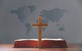 Cross with open Holy Bible on table with world map blur background. mission evangelism and gospel on world. Copy space for text,