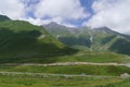 Cross pass on Georgian military road in summer and giant mountains covered with alpine meadows