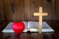 The cross and the red heart symbol are placed in front of the Bible. The concept of love for the Lord, prayer, education