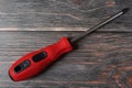 cross screwdriver with red handle on wooden background. Royalty Free Stock Photo