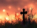 a cross silhouette standing in a field, with the warm glow of a sunset sky Royalty Free Stock Photo