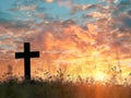 a cross silhouette standing in a field, with the warm glow of a sunset sky Royalty Free Stock Photo