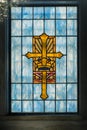 Cross in Stained glass window in church that is gold and blue christianity Royalty Free Stock Photo