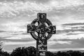 A cross is standing in a field with a cloudy sky in the background Royalty Free Stock Photo
