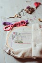 Cross stich set in process. hoop with embroidered pattern, scissors, canvas and colorful yarn