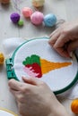 Cross stitch embroidery of color ice cream with woman hands and color balls of yarn on white wooden table Royalty Free Stock Photo