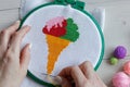 Cross stitch embroidery of color ice cream with woman hands and color balls of yarn on white wooden table Royalty Free Stock Photo