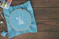 Cross-stitch pattern and embroidery accessories on wooden background, flat lay