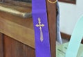 A cross symbol on a purple cloth for the priest is placed on a wooden platform for the confession of sins in Christianity