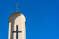 Cross on top of tower church against deep blue sky