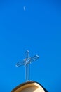 Cross on top of catholic tower church against deep blue sky and morning crescent