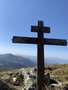 A cross on top of a mountain against a blue sky. A symbol of faith and hope outdoors. Sign of Christianity on a high mountain Royalty Free Stock Photo