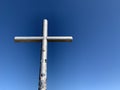 A cross on top of a mountain against a blue sky. A symbol of faith and hope outdoors. Sign of Christianity on a high mountain Royalty Free Stock Photo